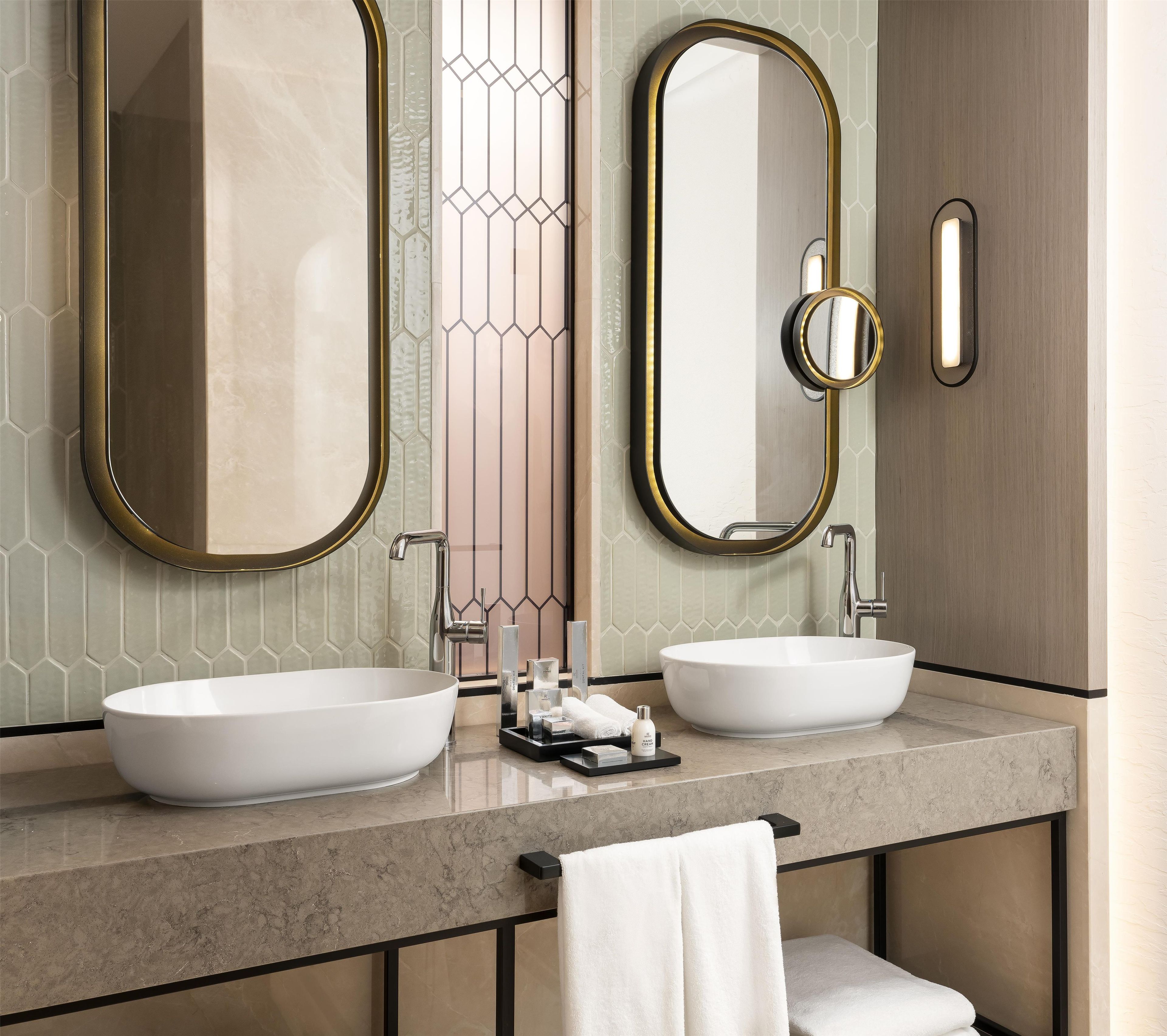Une salle de bain moderne avec deux lavabos, un grand miroir et un porte-serviettes.