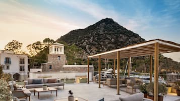 Terraza en la azotea con mobiliario exterior, una pérgola y vistas a la montaña.