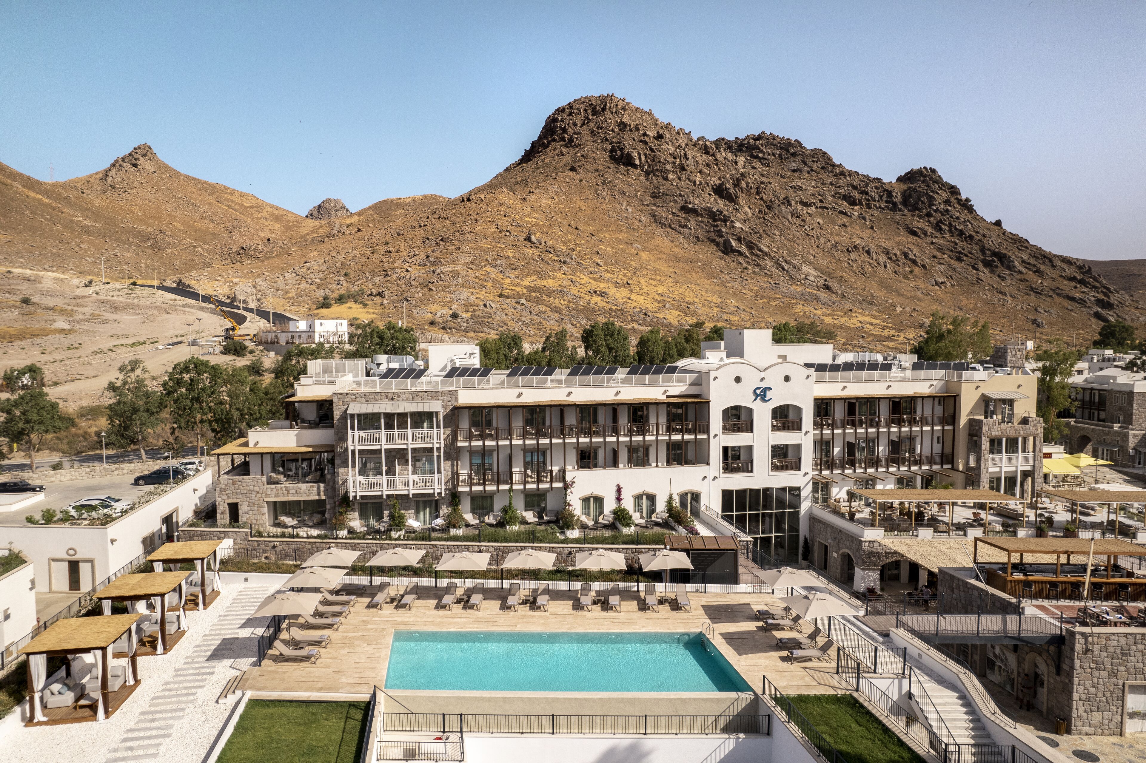 Un hotel con piscina, mobiliario exterior y vistas a la montaña.