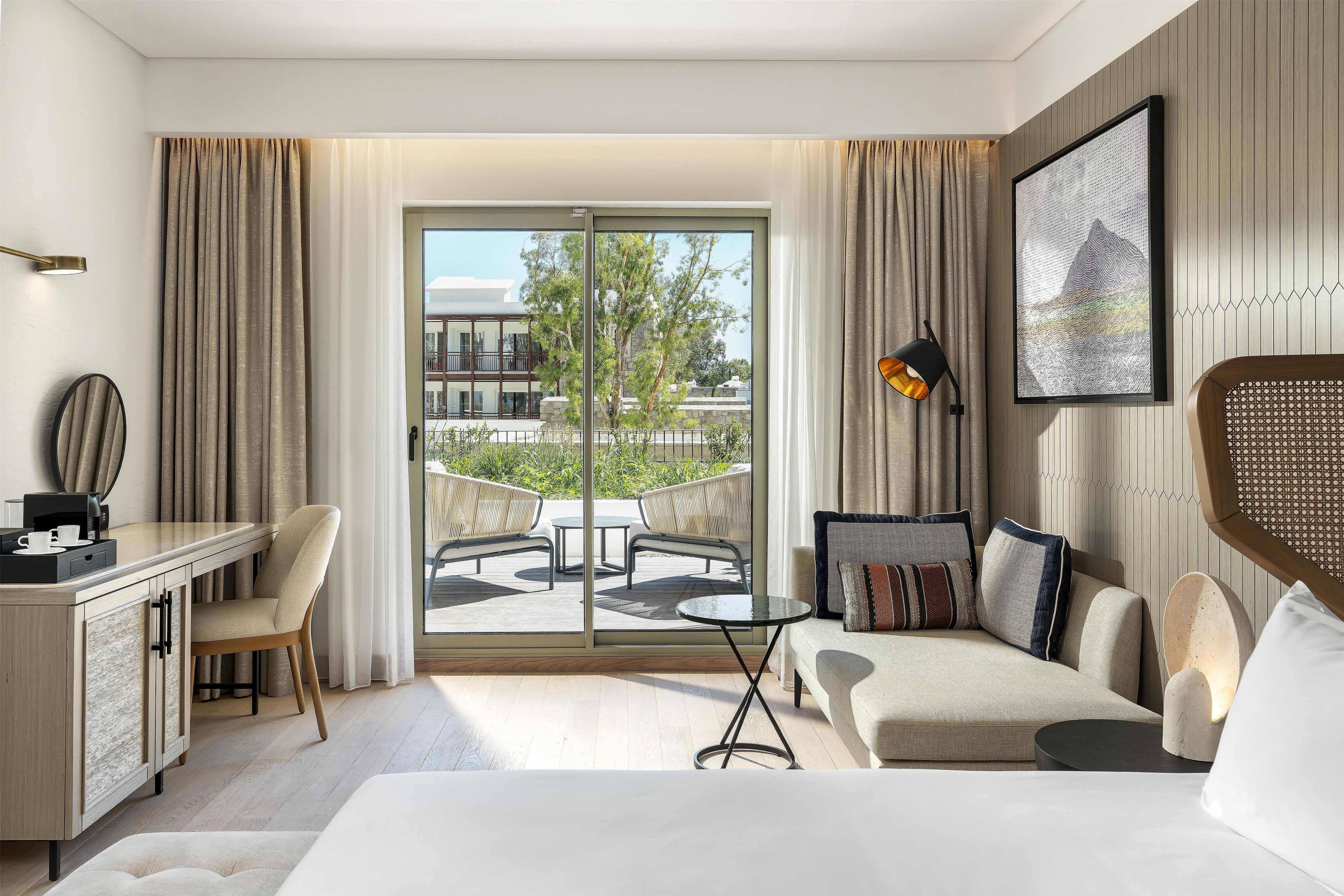 Una habitación de hotel con balcón, escritorio, sofá y cama.