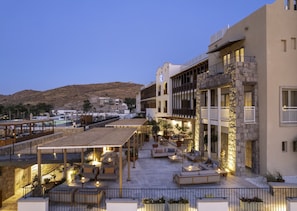 A hotel with outdoor seating areas, a pool, and a view of a hilly landscape.