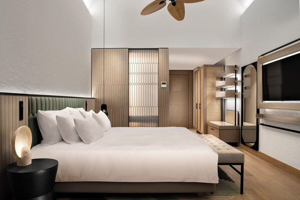 A modern bedroom with a large bed, a ceiling fan, and a built-in wardrobe.