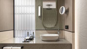 Un baño moderno con un espejo redondo, un lavabo sobre encimera y un perchero para toallas.