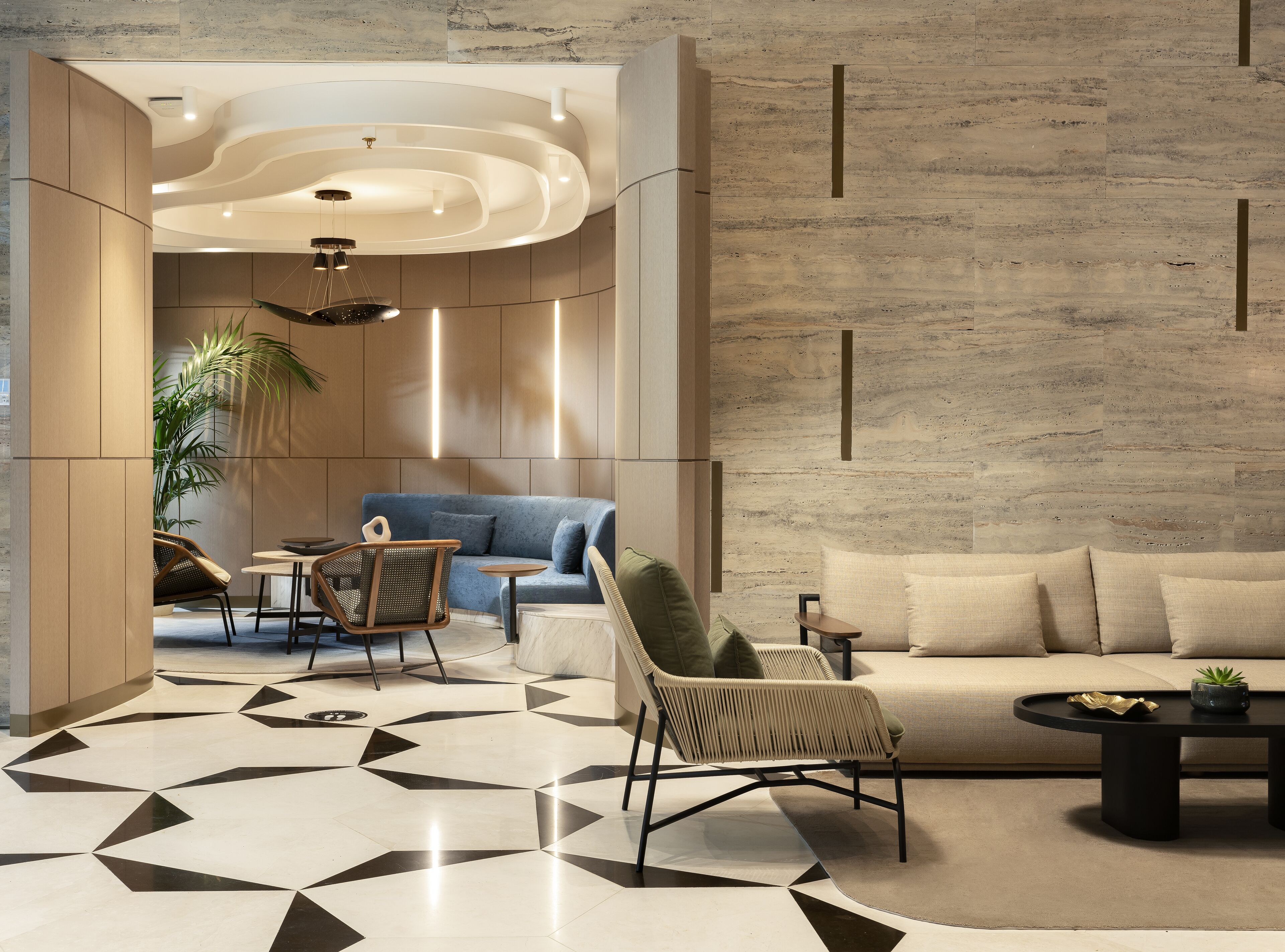 Een moderne woonkamer met een vloer met een geometrisch patroon, een blauwe bank en een beige bank.