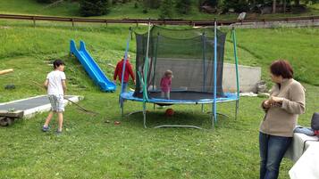 Un trampolino in un prato con uno scivolo nelle vicinanze.