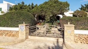 Une porte en pierre surmontée d’une arche en bois, entourée d’une végétation luxuriante et d’arbres.