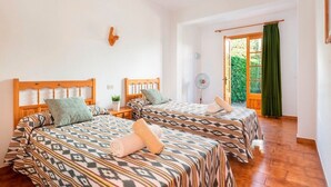 Une chambre avec deux lits, un ventilateur et une vue sur la verdure environnante.