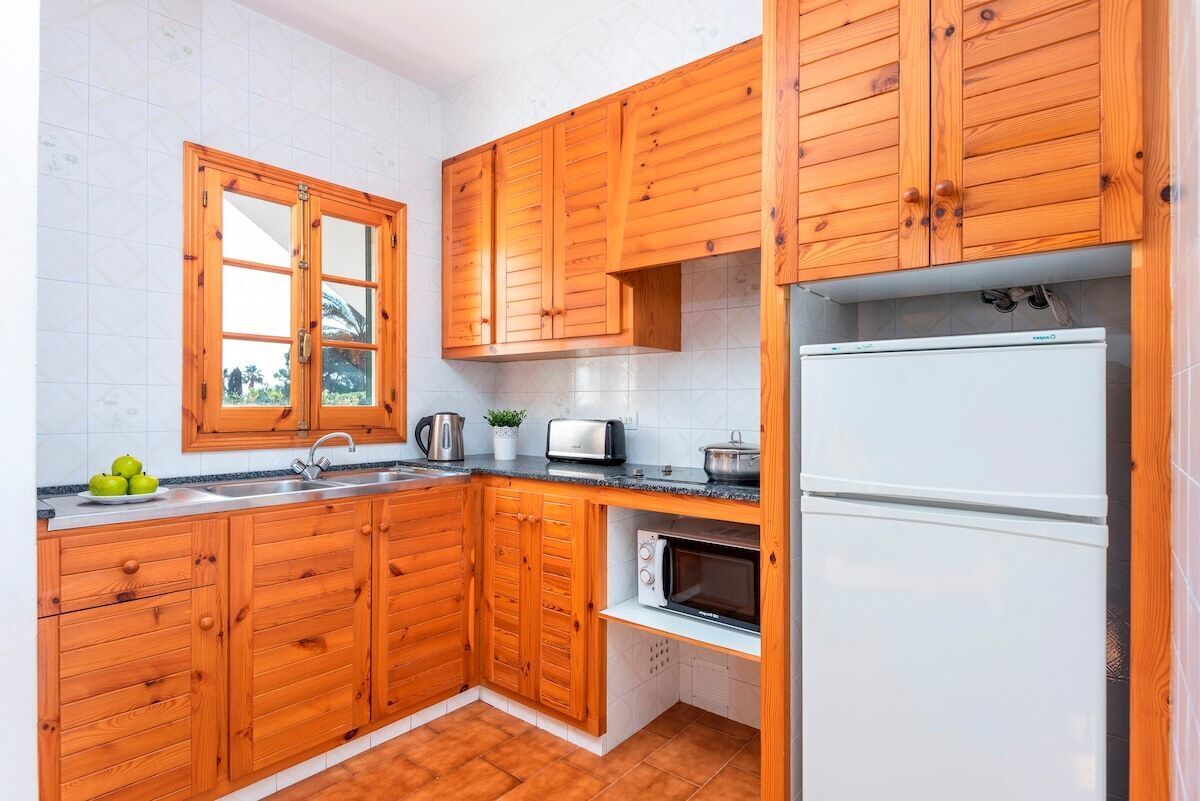 Une cuisine avec des meubles de rangement en bois, un four à micro-ondes, un grille-pain et un évier.