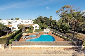 A modern villa with a swimming pool, surrounded by lush greenery and palm trees.