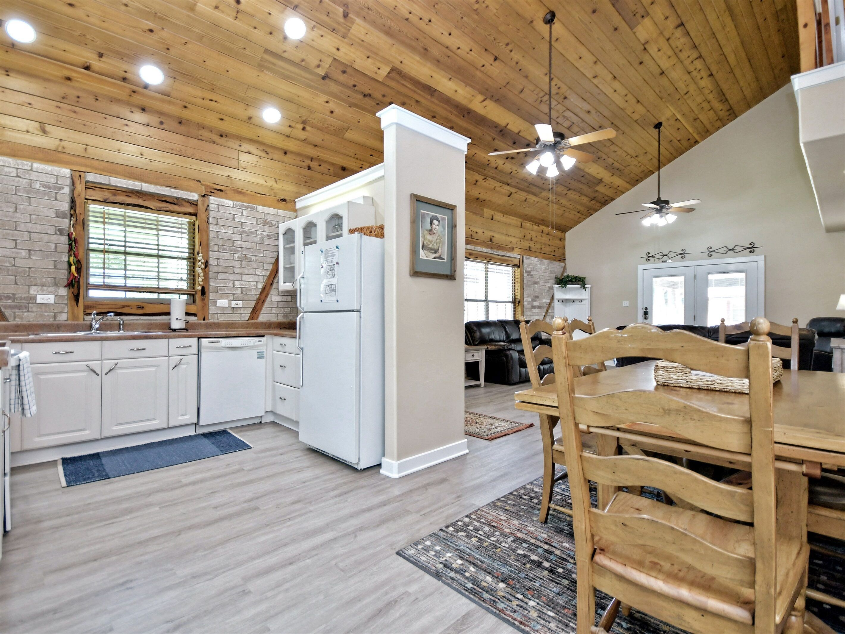 A kitchen with white cabinets, a refrigerator, and a dining area with a wooden table and chairs.