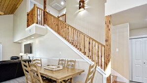 Un coin repas avec une table et des chaises en bois, un petit tapis et un escalier avec des rampes en bois.