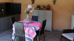 A dining area with a table set for two, a TV mounted on the wall, and decorative cow skulls on the wall. - Charming independent studio in Martigues town center, swimming pool, spa (Martigues)