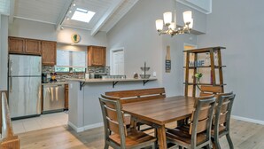 Eine moderne Küche mit Holzschränken, einem Edelstahlkühlschrank und einem Essbereich mit Holztisch und -stühlen.