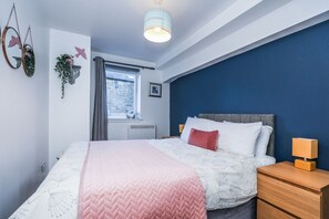 A bedroom with a bed, bedside tables, a window, and a blue accent wall.