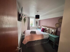A bedroom with a bed, bedside table, lamp, and a hanging plant. - Old Town Gem - Castle, Dark History, Uni (Edinburgh)