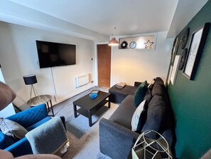 A living room with a sofa, a coffee table, a TV, and a lamp. - Old Town Gem - Castle, Dark History, Uni (Edinburgh)