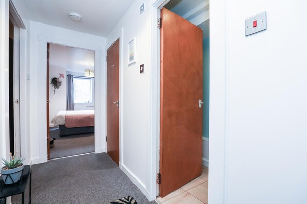 Un couloir avec un lit, une porte et un interrupteur fixé au mur.