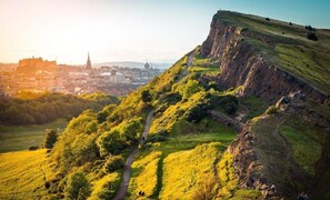 A hill with a path leading to a viewpoint overlooking a cityscape.
