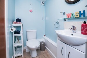 Ein Badezimmer mit Toilette, Waschbecken und Regalen.