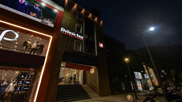 Un hotel llamado 'Deluxe Inn' con un letrero, una escalera que lleva a la entrada y un escaparate visible con maniquíes.
