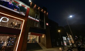 A hotel named 'Deluxe Inn' with a signboard, a staircase leading to the entrance, and a visible storefront with mannequins.