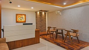 Un área de recepción con un mostrador de madera, pared de piedra, una mesa redonda con sillas y un ventilador de techo.