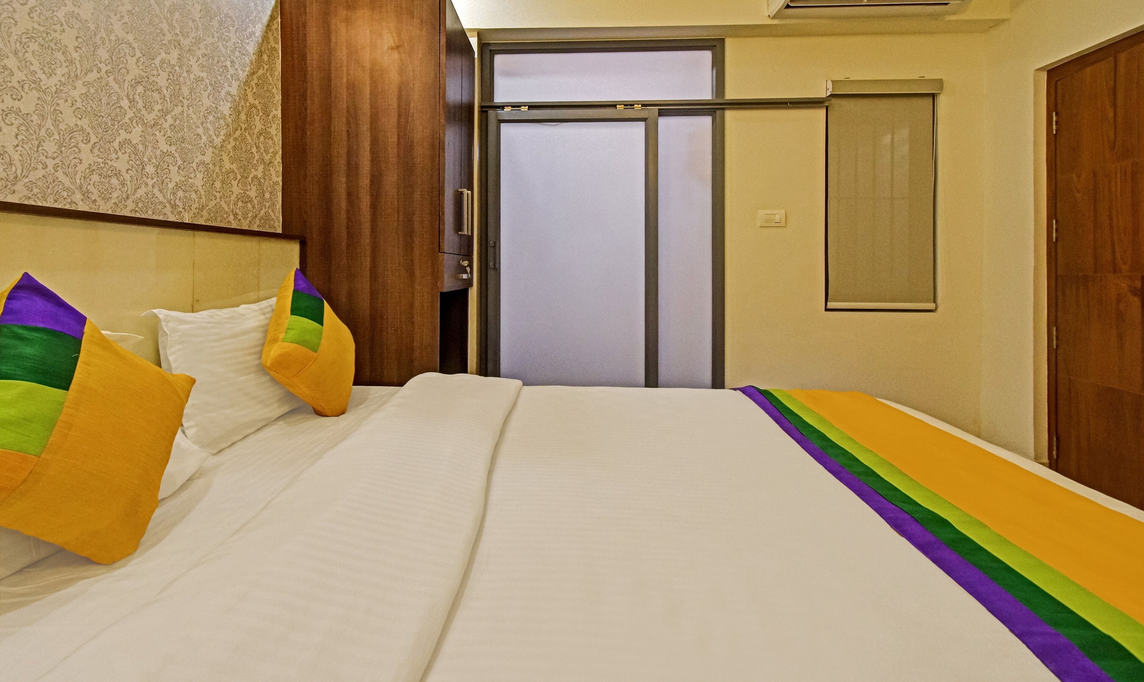 A hotel room with a bed, a wardrobe, and a door.