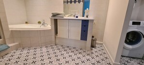 A bathroom with a sink, mirror, towel rack, and a washing machine.