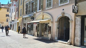 Una calle con un edificio que tiene una gran entrada arqueada, un letrero de pub y una tienda con fachada de vidrio.