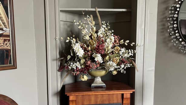 A fireplace with a flower arrangement, a mirror, and a chair. - Cozy and artistic Pied-a-Terre, perfect for a weekend romantic getaway. (Little Falls)