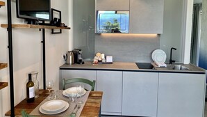 A compact kitchen with a built-in TV, a coffee machine, and a sink. - Maisonette (Tenno)