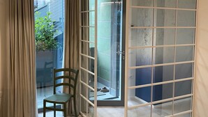 A room with a sliding glass door leading to a balcony, a chair, and a bed. - Maisonette (Tenno)
