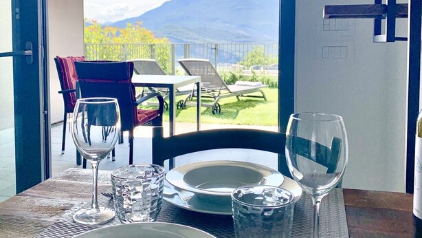 A dining table set with plates, glasses, and cutlery, overlooking a mountain view. - Maisonette (Tenno)