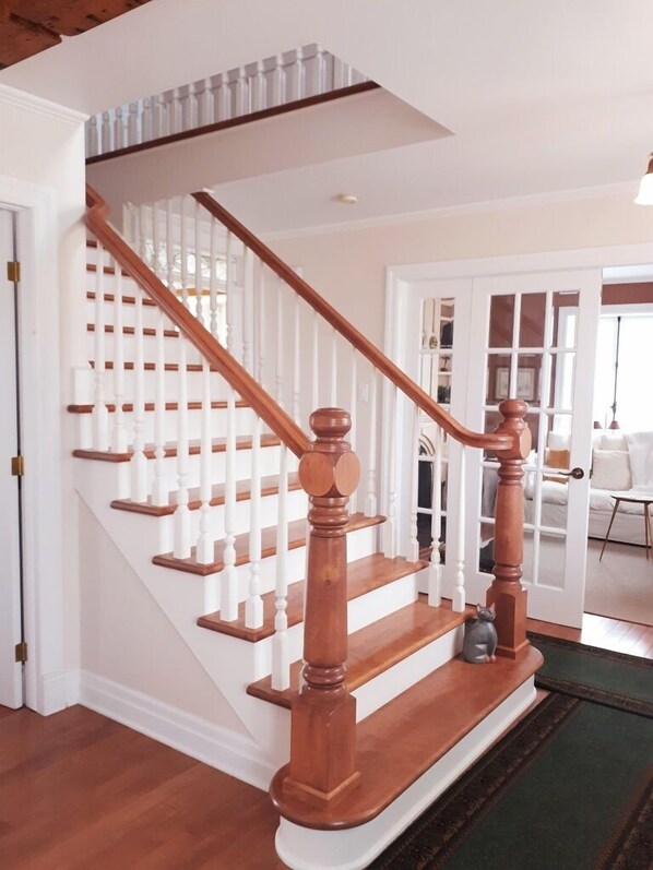 Una escalera de madera con barandillas blancas y un pasamanos de madera oscura.