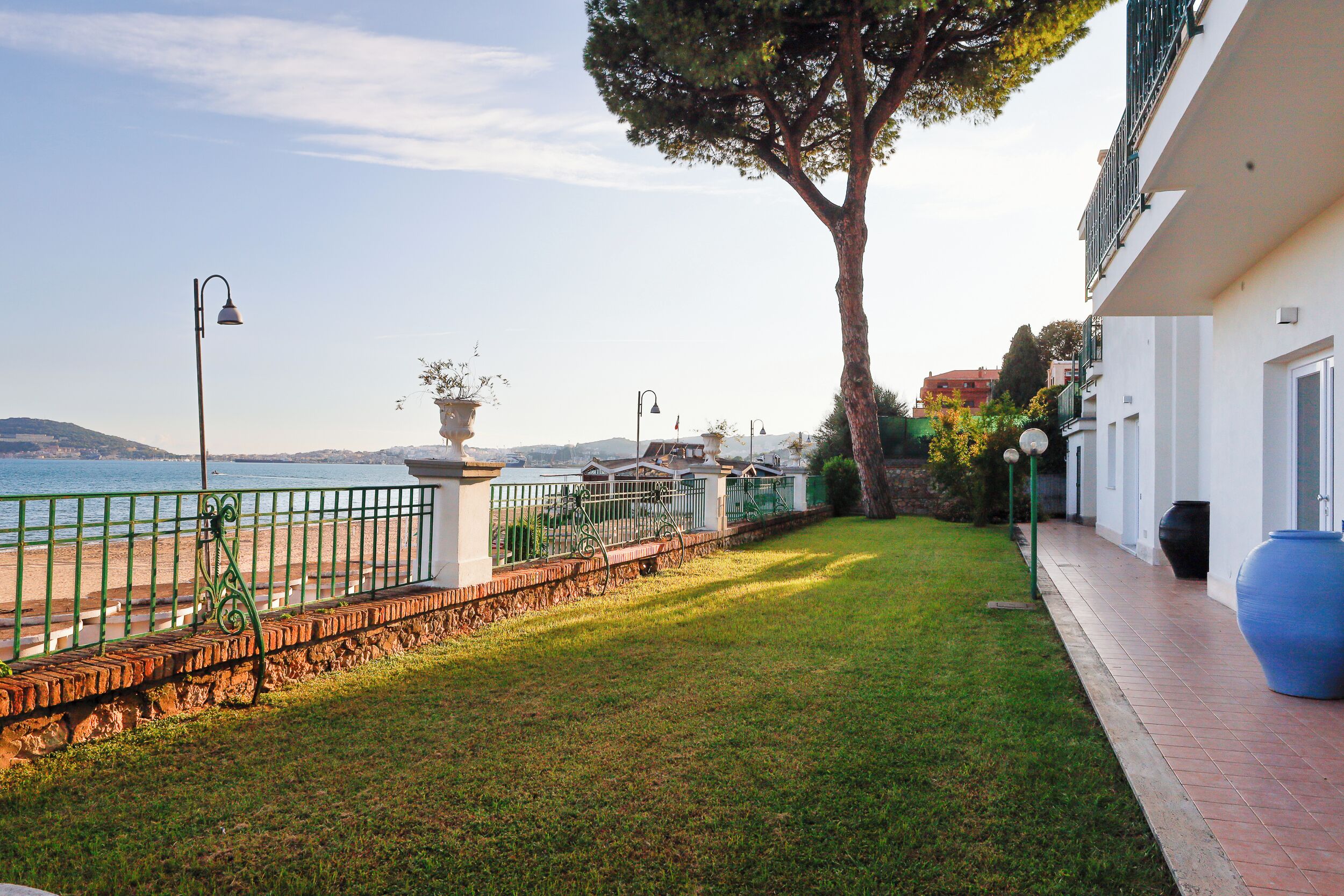 Une vue sur la côte, avec une pelouse verdoyante, une clôture en métal et un bâtiment doté d’un balcon.