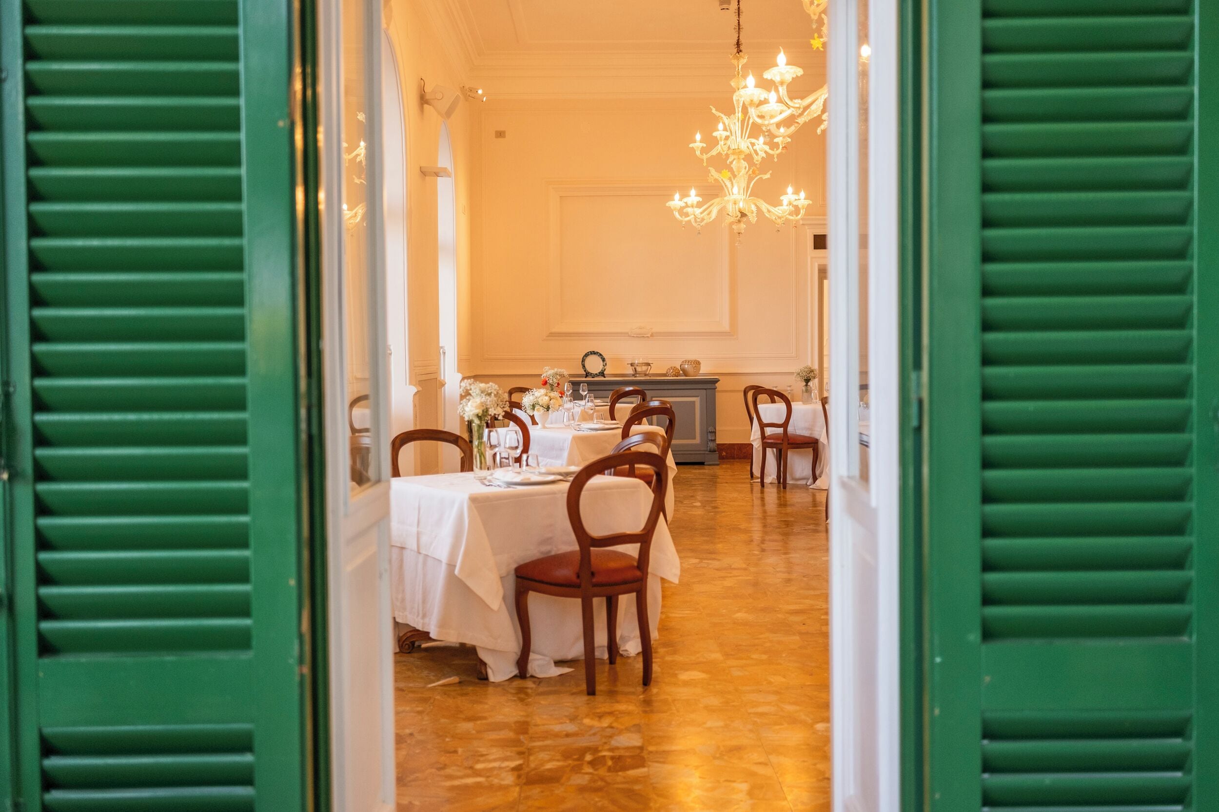 Comedor con mesas dispuestas para una comida, sillas y una araña.