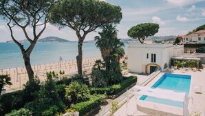 A pool area with a view of the sea, surrounded by greenery and a building with a white facade. - Villa Maria Teresa Boutique Hotel (Formia)