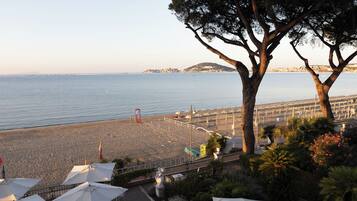 Una spiaggia con ombrelloni, una recinzione e un albero.