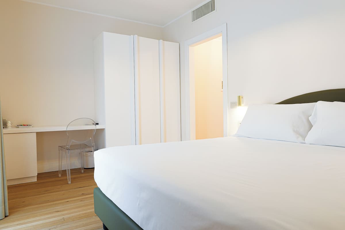 Hotellihuone, jossa on sänky, työpöytä ja tuoli.