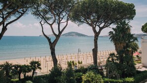 A beach with umbrellas and trees, a clear sky, and a distant island. - Villa Maria Teresa Boutique Hotel (Formia)