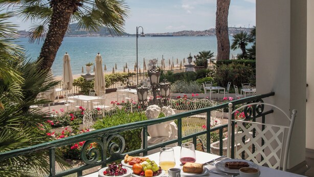 A table set with breakfast items, overlooking a coastal view with a palm tree and a large tree. - Villa Maria Teresa Boutique Hotel (Formia)
