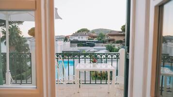 En balkong med ett bord och stolar, med utsikt över en swimmingpool och bostadshus.