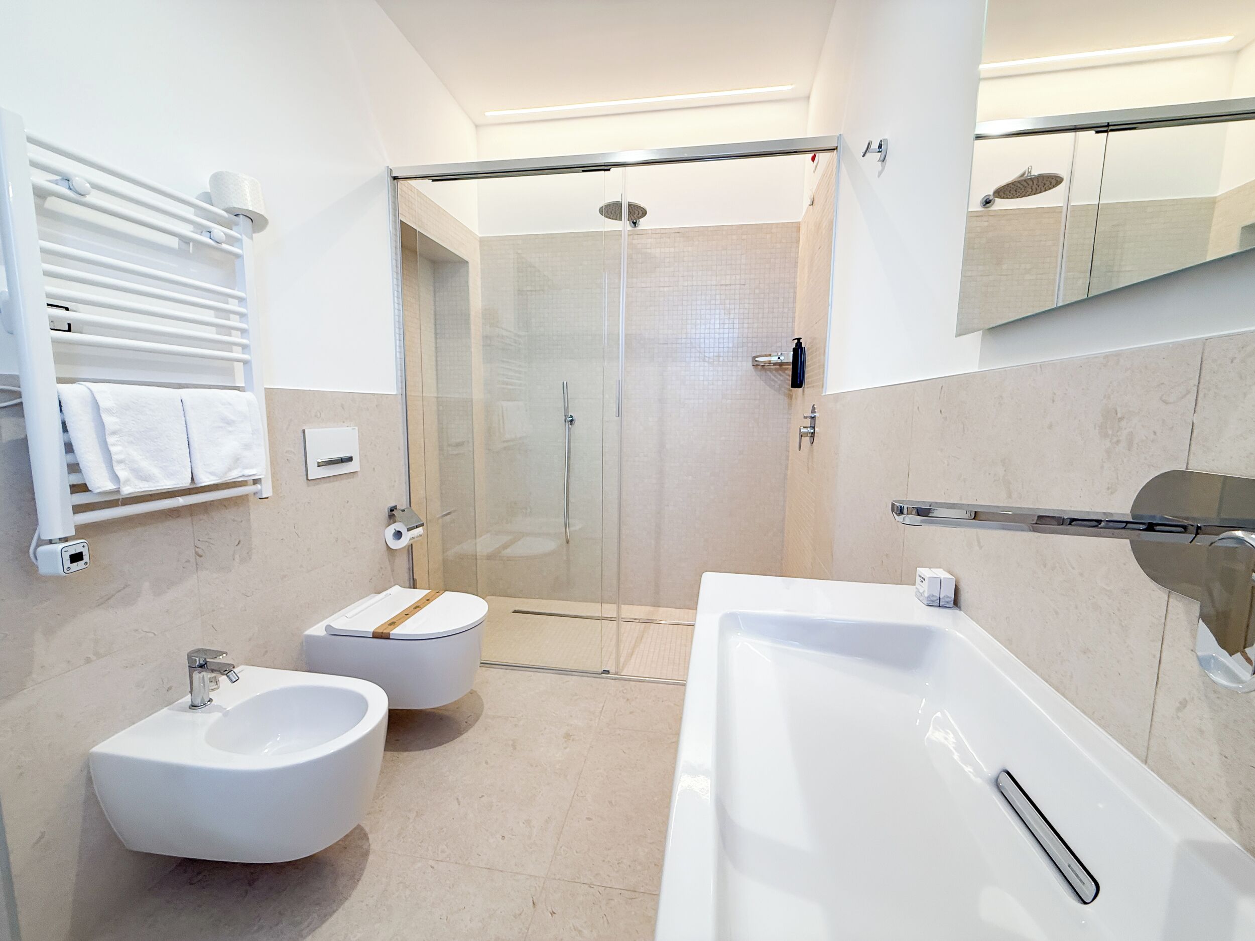 Un baño moderno con bañera, dos lavamanos, ducha e inodoro.