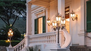 A grand entrance with a white facade, green shutters, and a curved staircase leading up to a balcony. - Villa Maria Teresa Boutique Hotel (Formia)