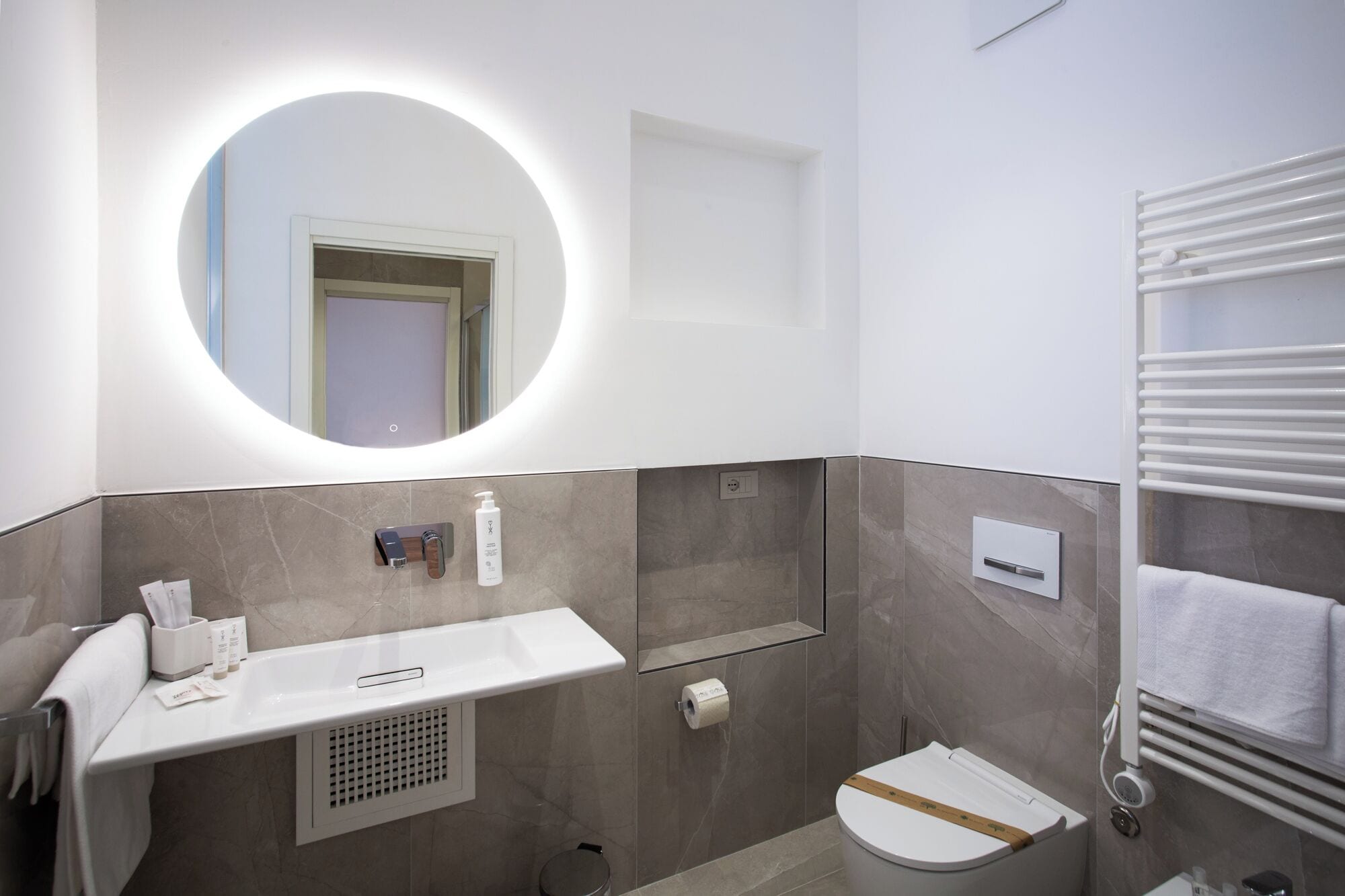 A modern bathroom with a vanity, mirror, towel rack, toilet, and a shower area.
