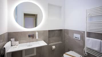 A modern bathroom with a vanity, mirror, towel rack, toilet, and a shower area.