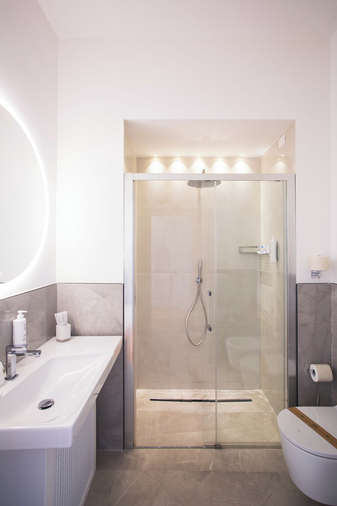 A modern bathroom with a glass-enclosed shower, a large white sink, and a toilet.