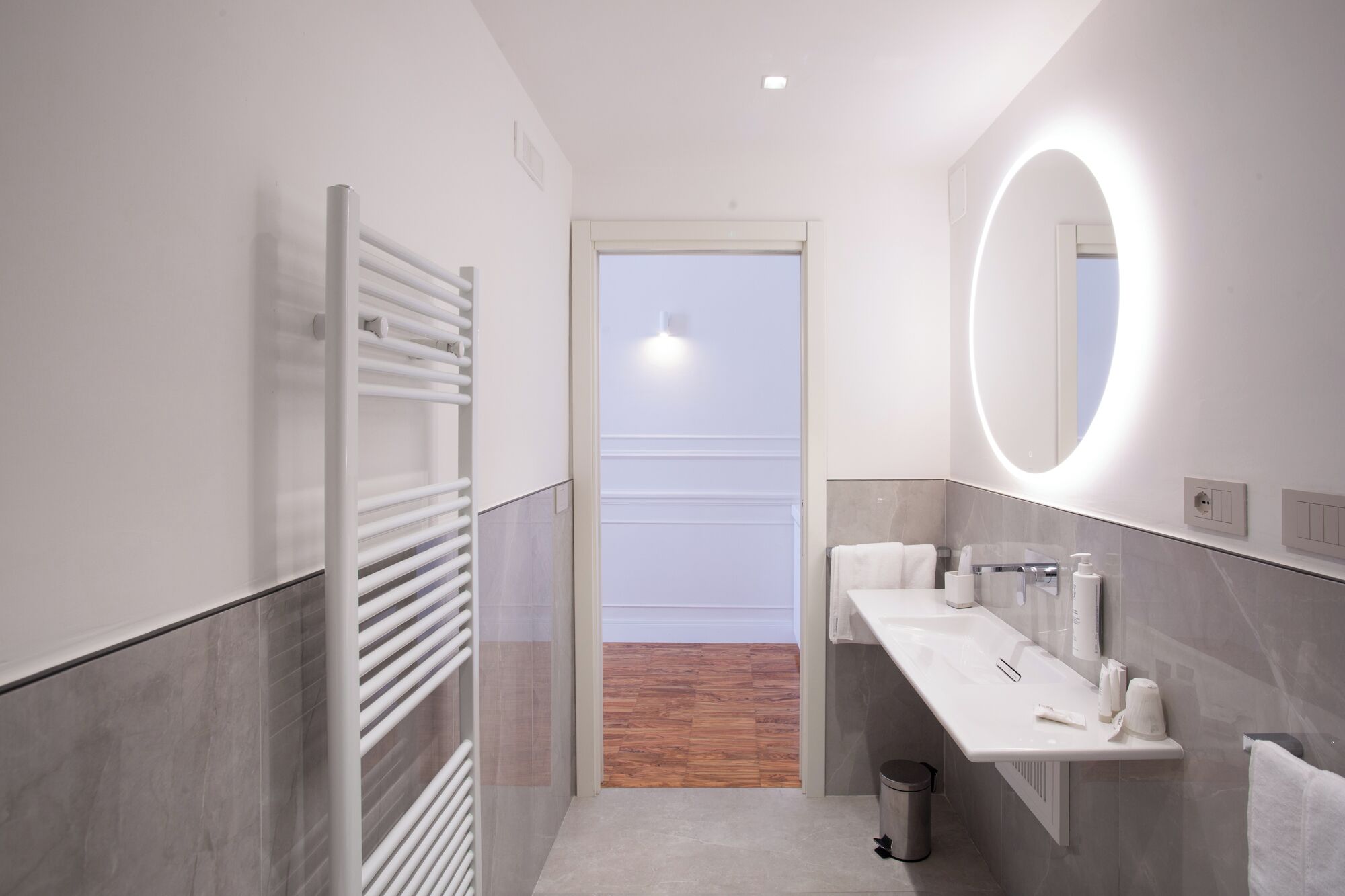 Un baño moderno con lavamanos, espejo y toallero blancos.