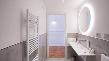 Un baño moderno con lavamanos, espejo y toallero blancos.