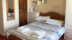 Une chambre à coucher avec un lit, une armoire, un miroir et un ventilateur de plafond.